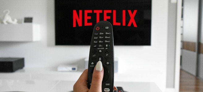 person holding remote and watching netflix on tv